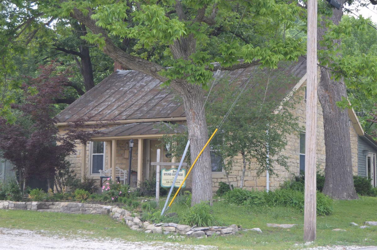 A low stone building under large shade trees in the Grafton historic district